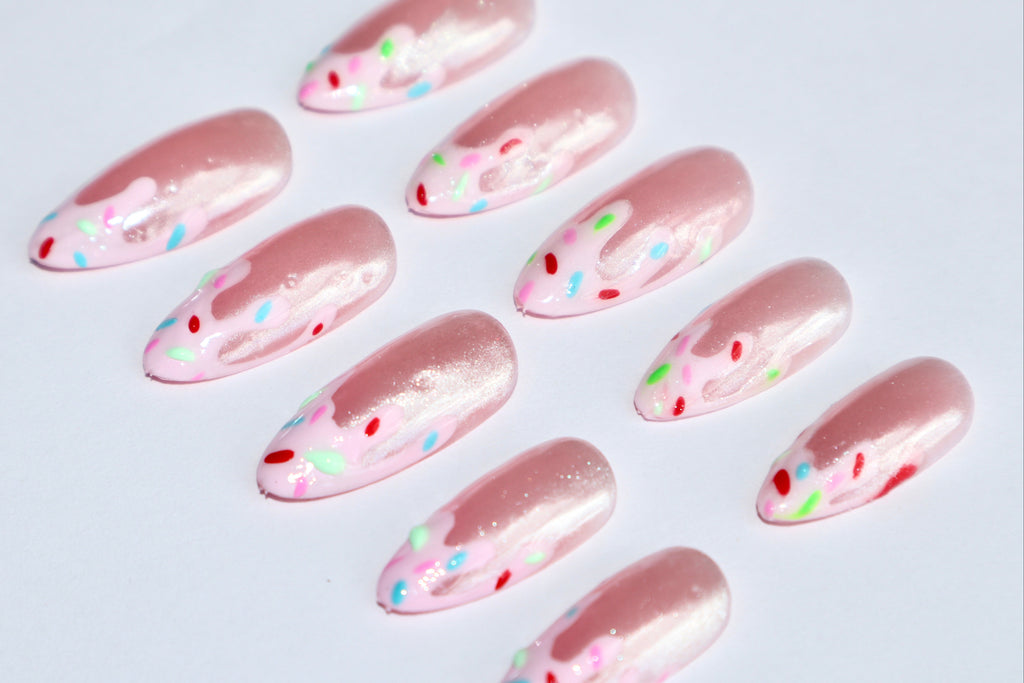 Pink nail art designs with colorful dots on a light gray background